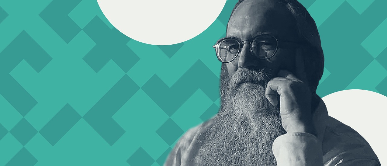 a man with a long beard wearing glasses with a hand on his face